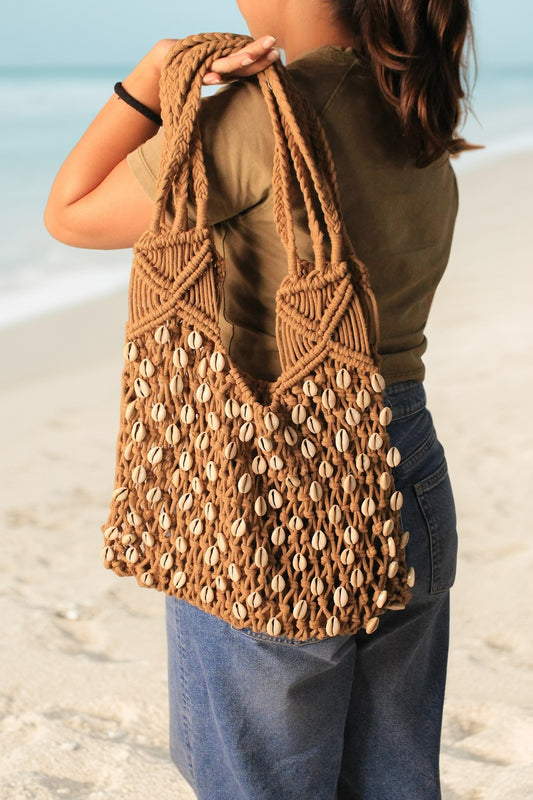 macrame beach bag on a girl shoulder in a brown color for everyday use.
