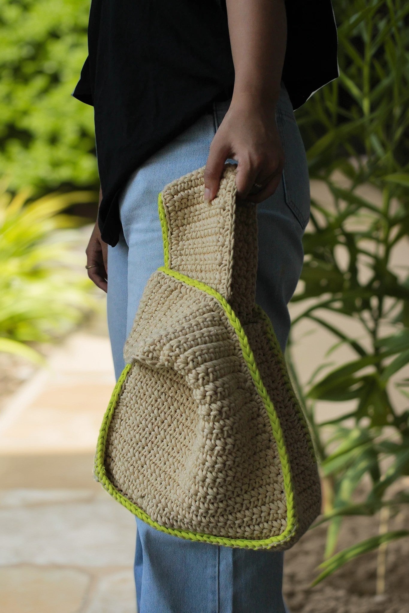 A girl holding a beige color bag with green border for casual outings.