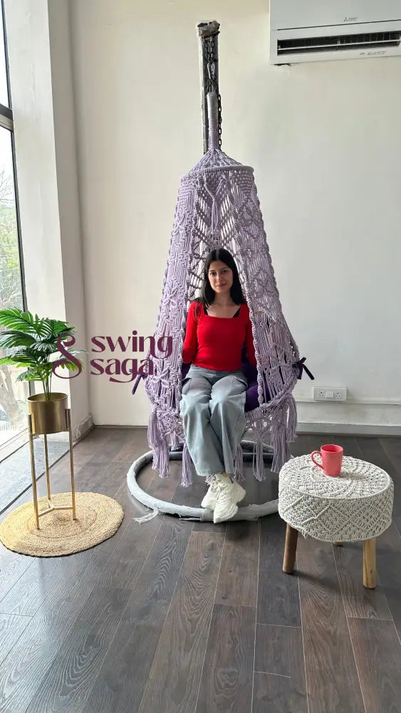 front view of a girl on a macrame swing with stand in an aesthetic setup.