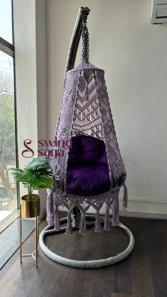 Front view of purple swing with stand in an aesthetic setup. swing hanged on a stand in round shape