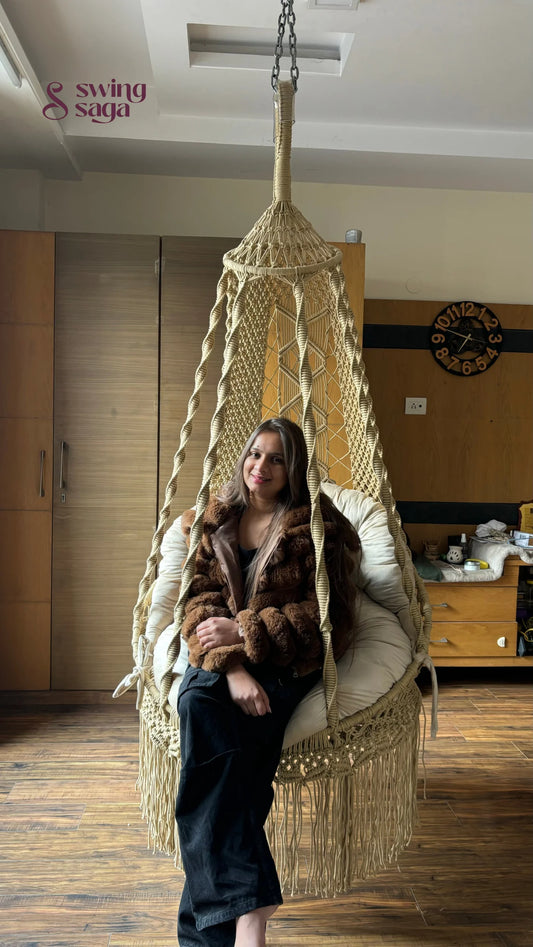 A girl is sitting on a macrame chair hammock swing