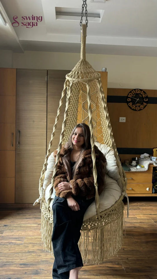 A girl is sitting on a macrame chair hammock swing