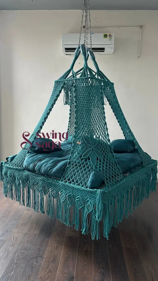 Lagoon frame hanging swing in teal blue with handcrafted macrame design, square bed-style seat, and tassel details.