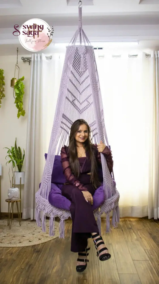 A girl is sitting on a purple chair hammock hanging swing.