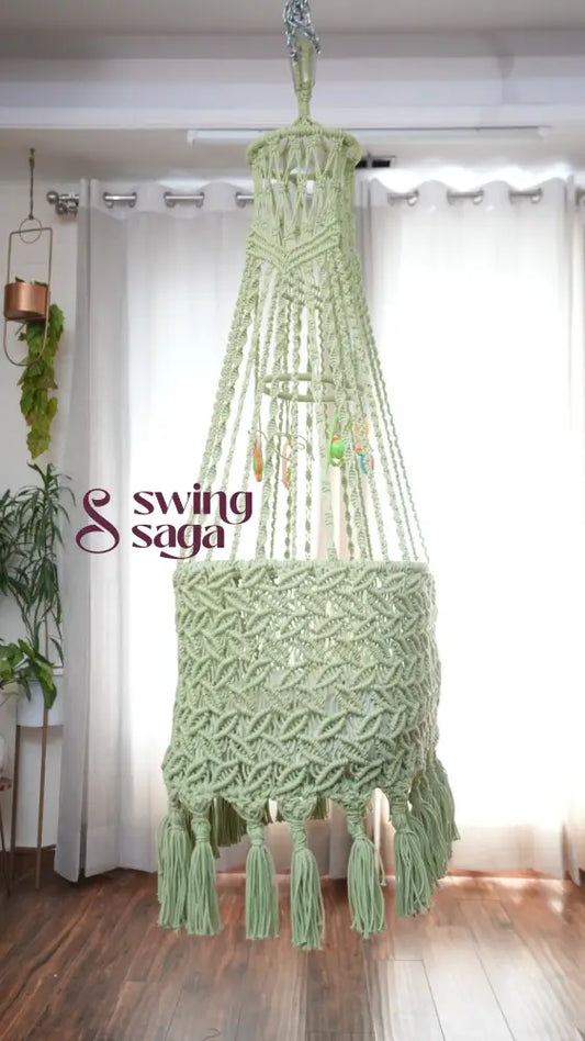 Side image of a lime green colored macrame baby cradle in a room setting.