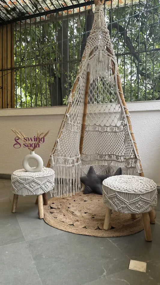 Handmade macrame teepee in white color placed in an outdoor setting.