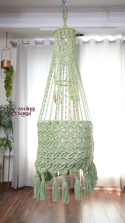 Side image of a lime green colored macrame baby cradle in a room setting.