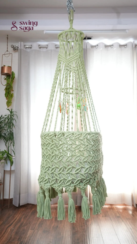 Side image of a lime green colored macrame baby cradle in a room setting.