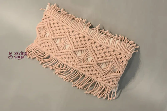 Macrame wall hanging with geometric pattern and fringe on a plain background