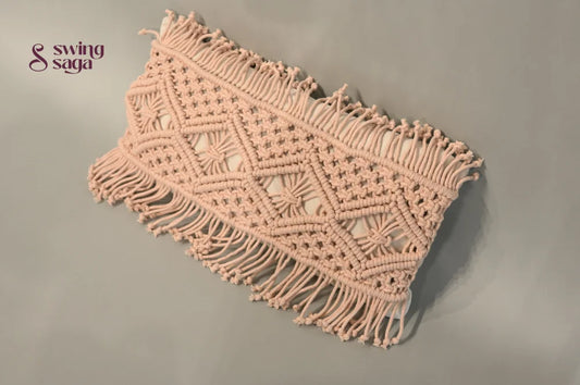 Macrame wall hanging with geometric pattern and fringe on a plain background