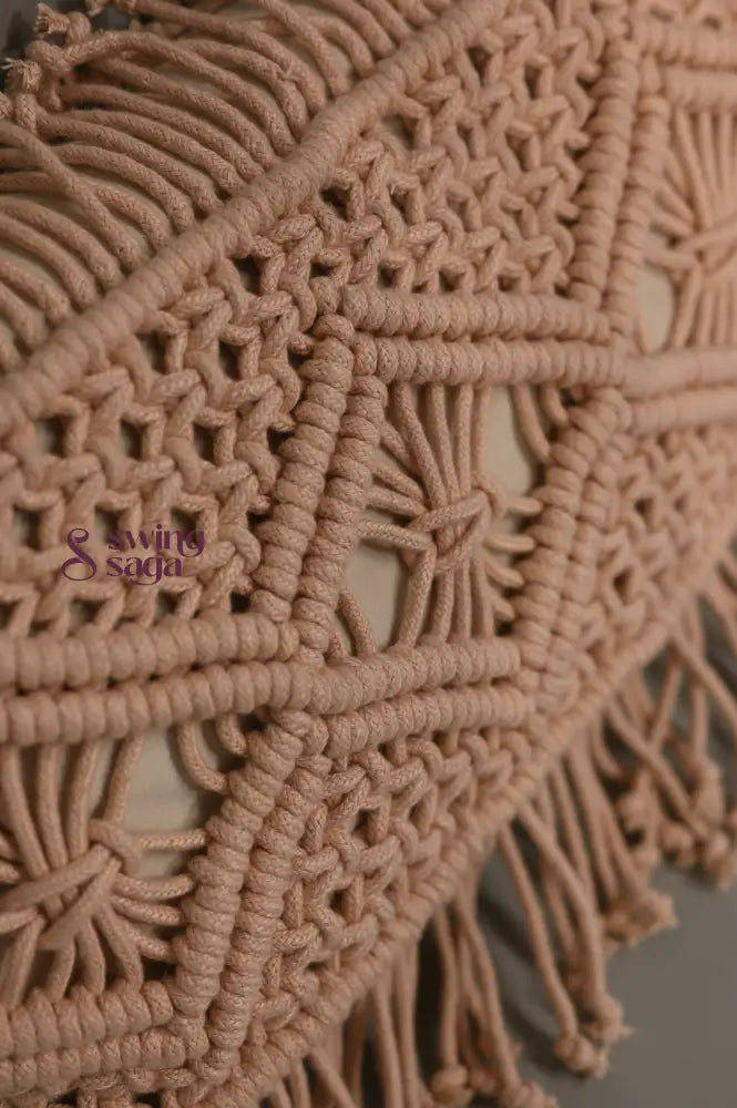 Close-up of a beige macrame wall hanging with intricate patterns and fringes.