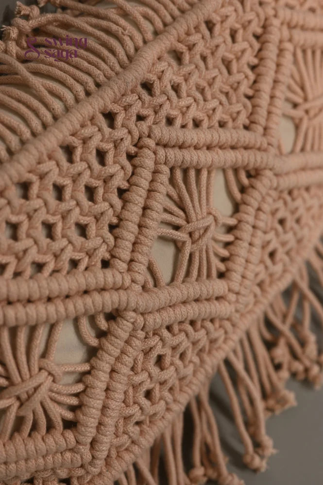 Close-up of a beige macrame wall hanging with intricate patterns and fringes.