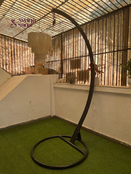 black metal stand with curved arm on a faux grass mat.