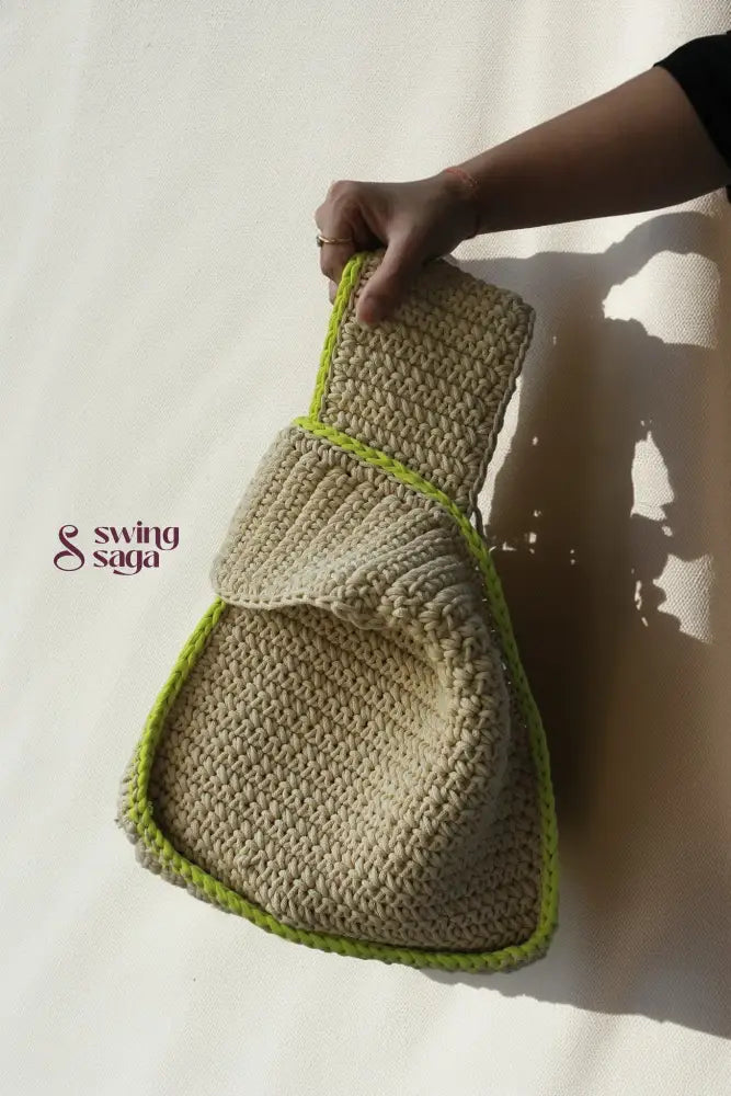 a girl holding a modern sling bag in beige color with green border.