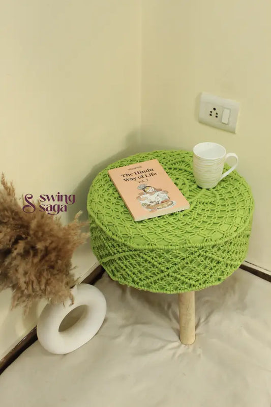 Stylish green macrame pouf with handcrafted texture and durable wooden legs.
