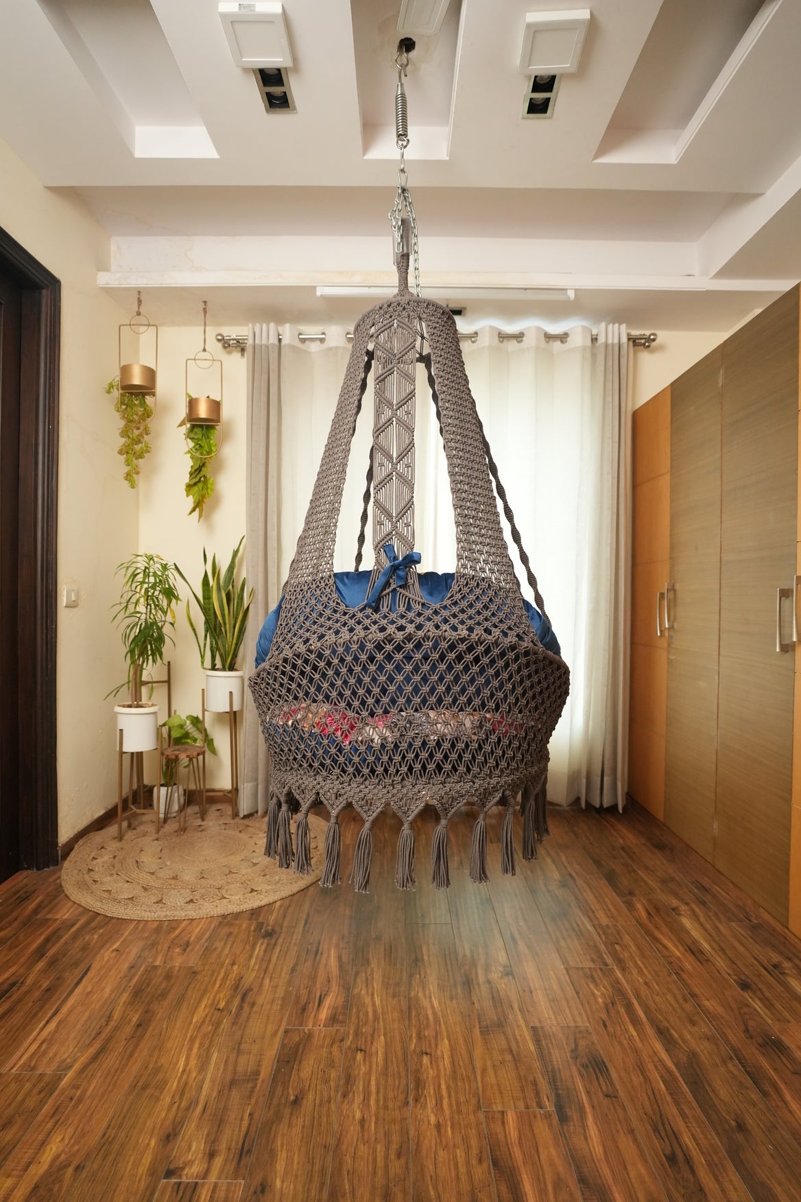 brown chair swing hanging in a wooden flooring room.