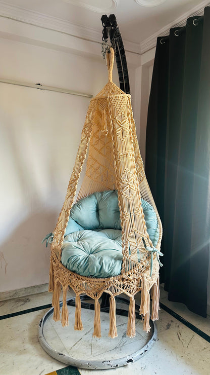 chair swing in cream color with blue mattress with a metal stand.