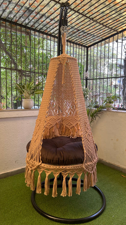 beige macrame swing with metal stand.