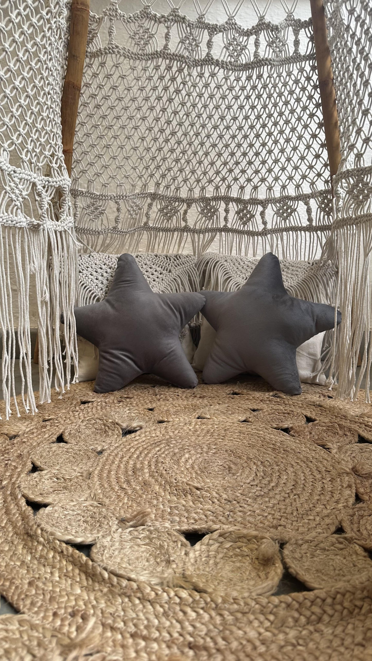 pair of grey star cushions inside of a macrame white teepee.