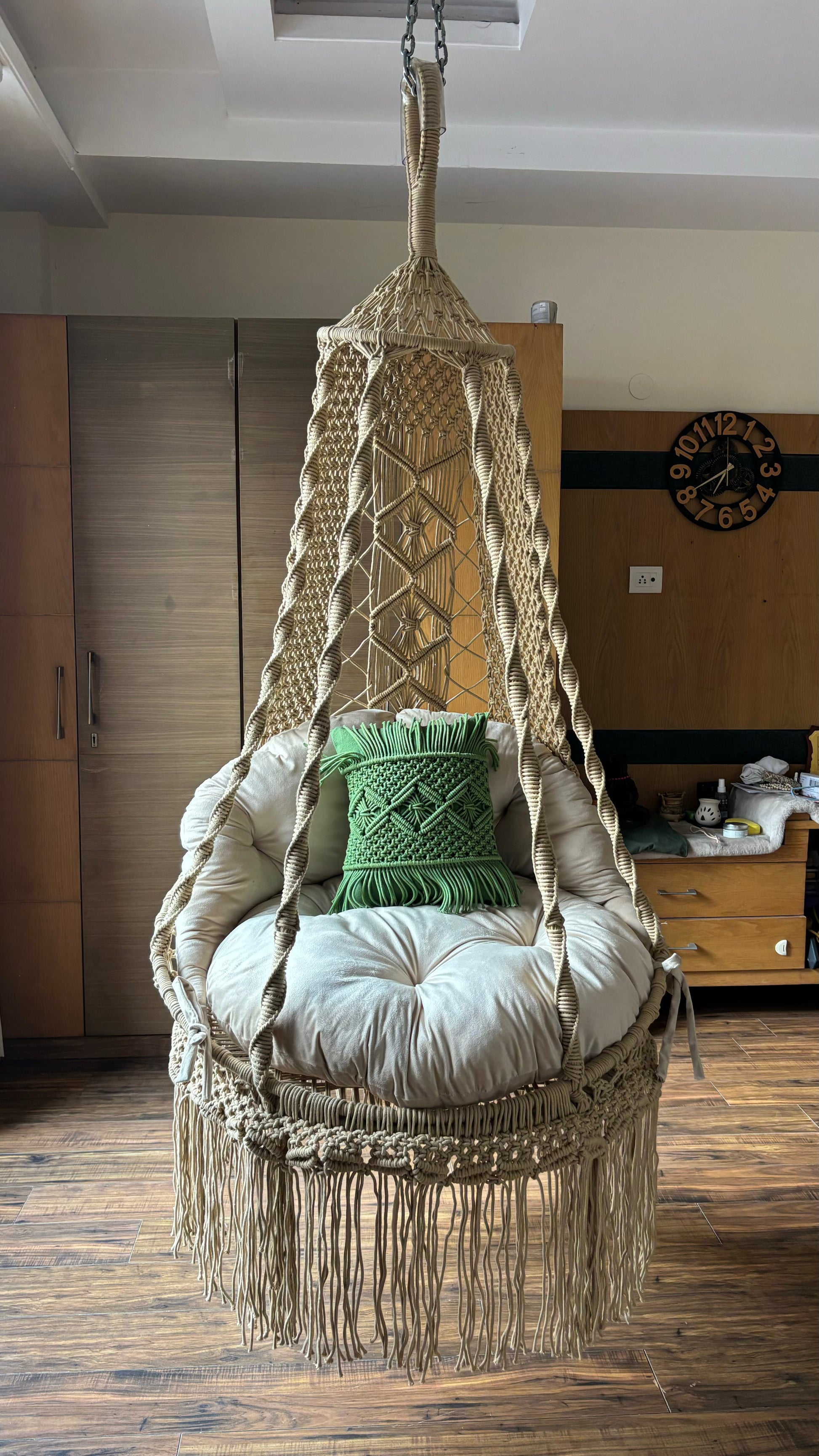Hanging macrame chair with cushions in a cozy room setting