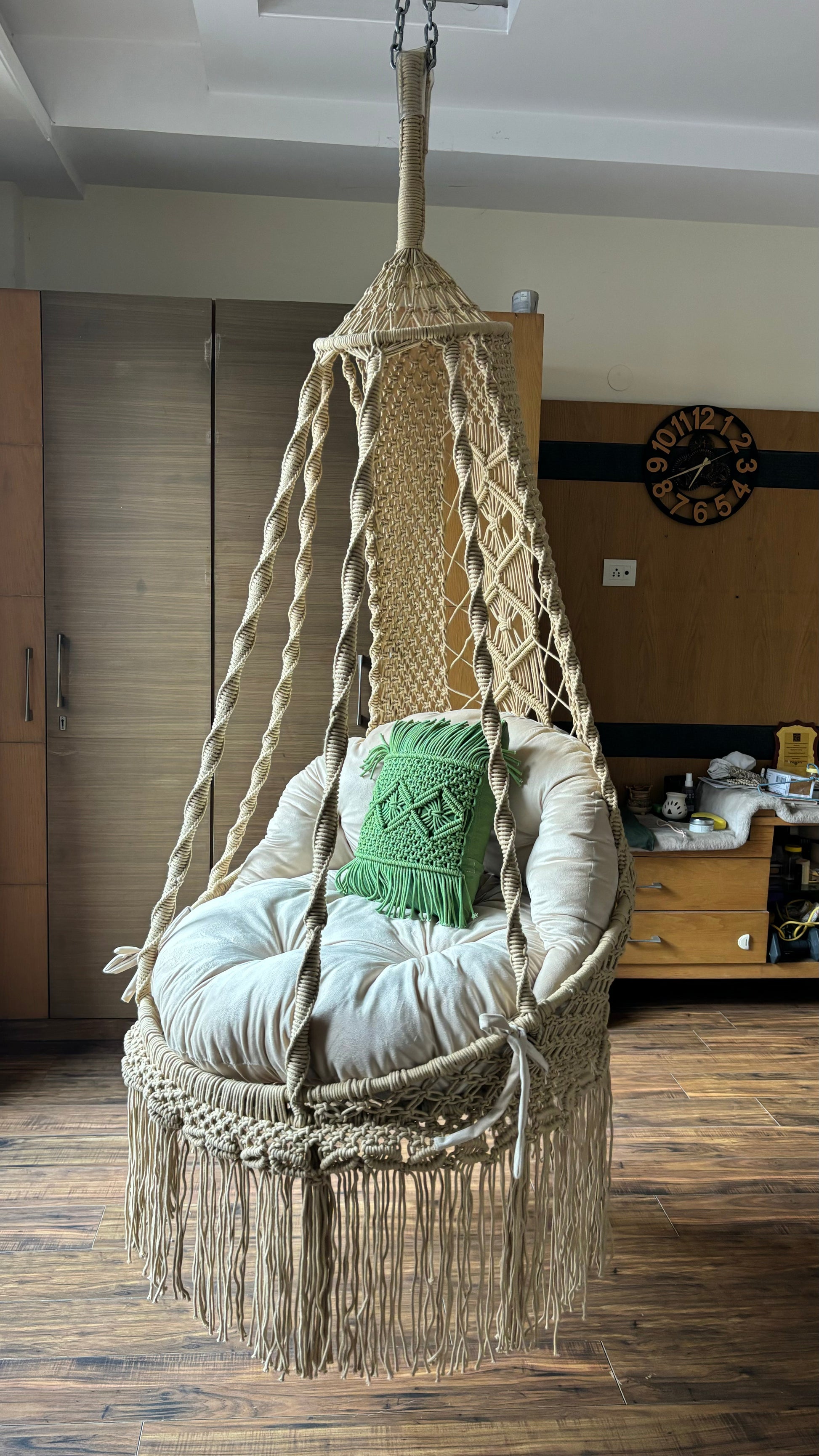 Hanging macrame chair with cushions in a cozy room setting