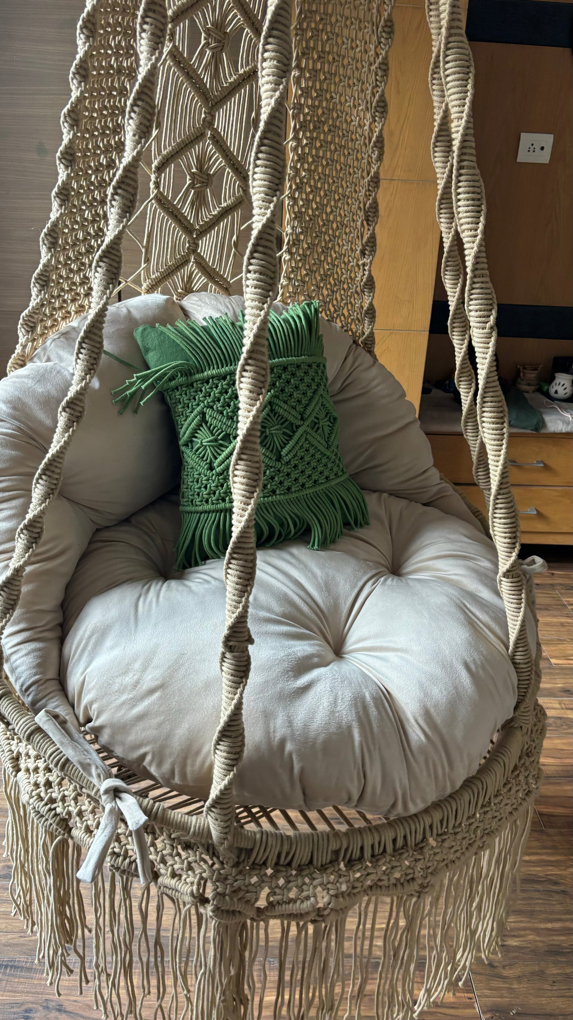 Close up shot of a  macrame chair with a green cushion