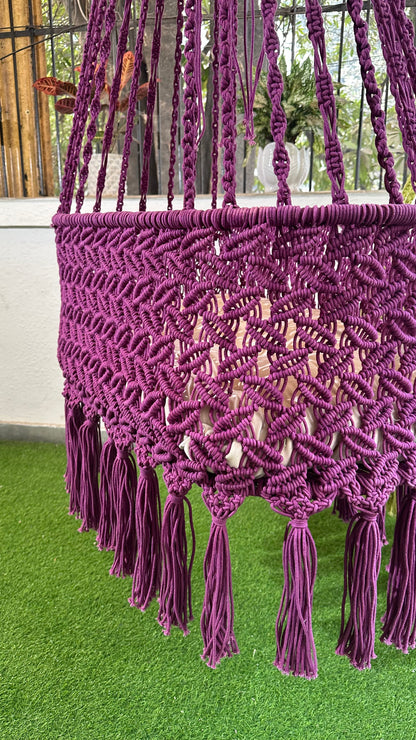 Detailed view of handcrafted purple macrame swing chair showing woven knot design and decorative tassels.