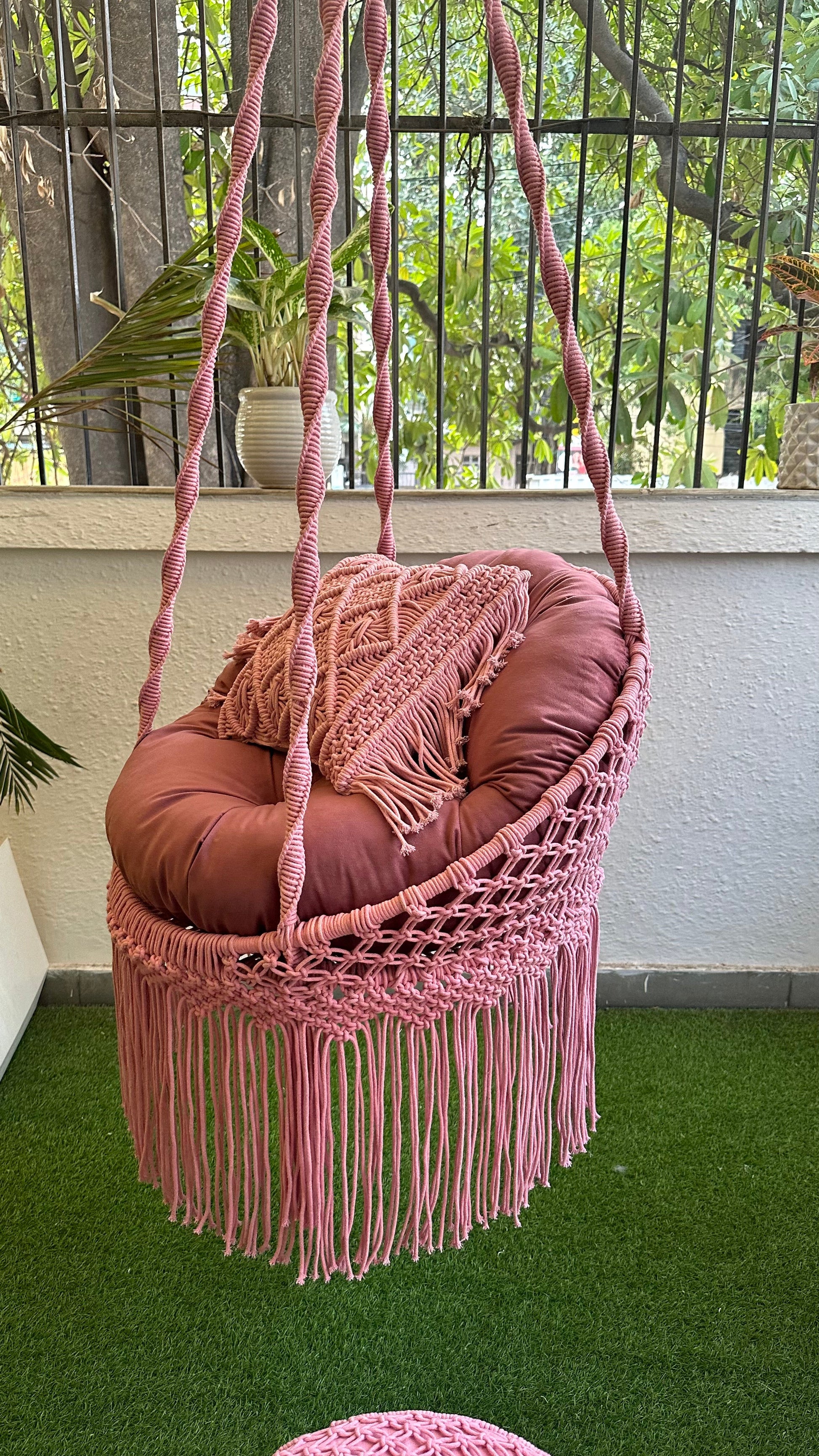 Cute pink macrame chair swing adding charm to an enclosed balcony