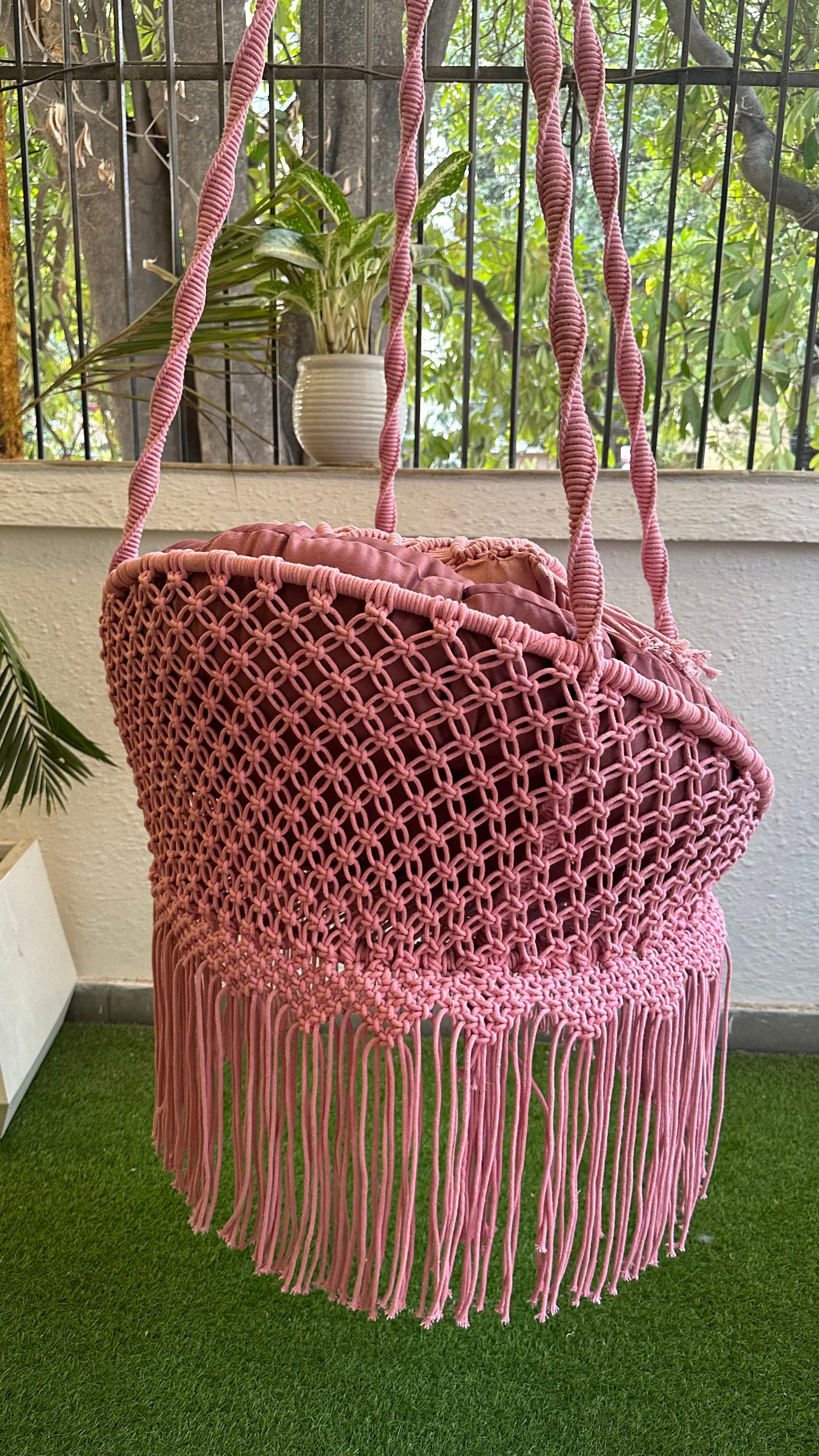 Compact pink macrame hanging chair for small indoor balcony décor