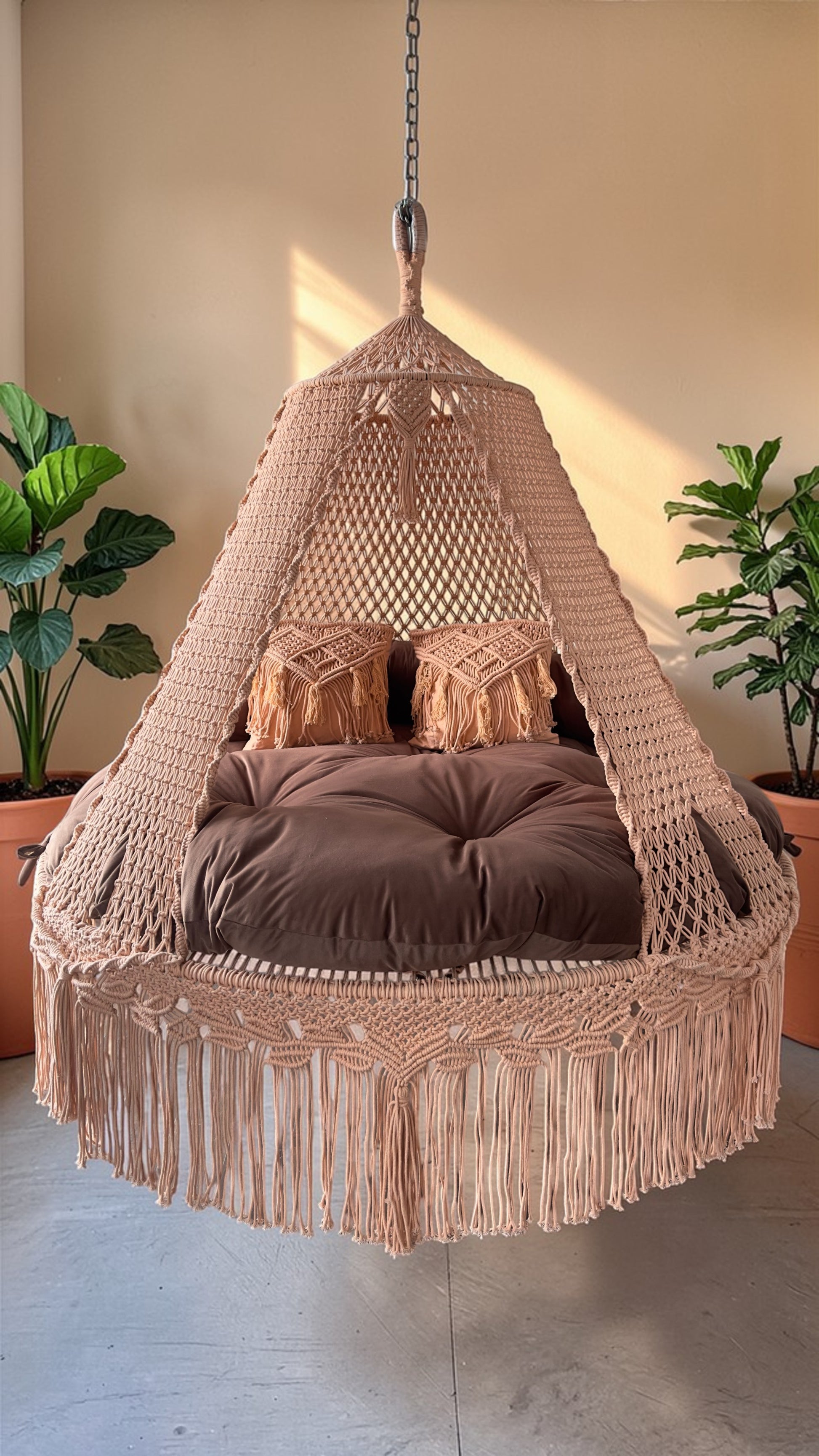 Hanging macrame chair with brown cushion in a room with plants