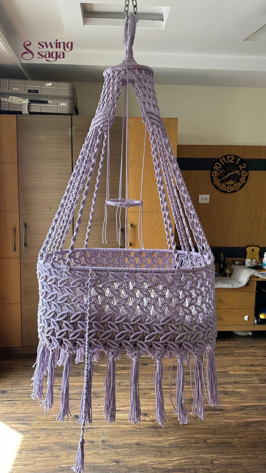 Macrame handcrafted baby bassinet in lavender color in a room setting. 