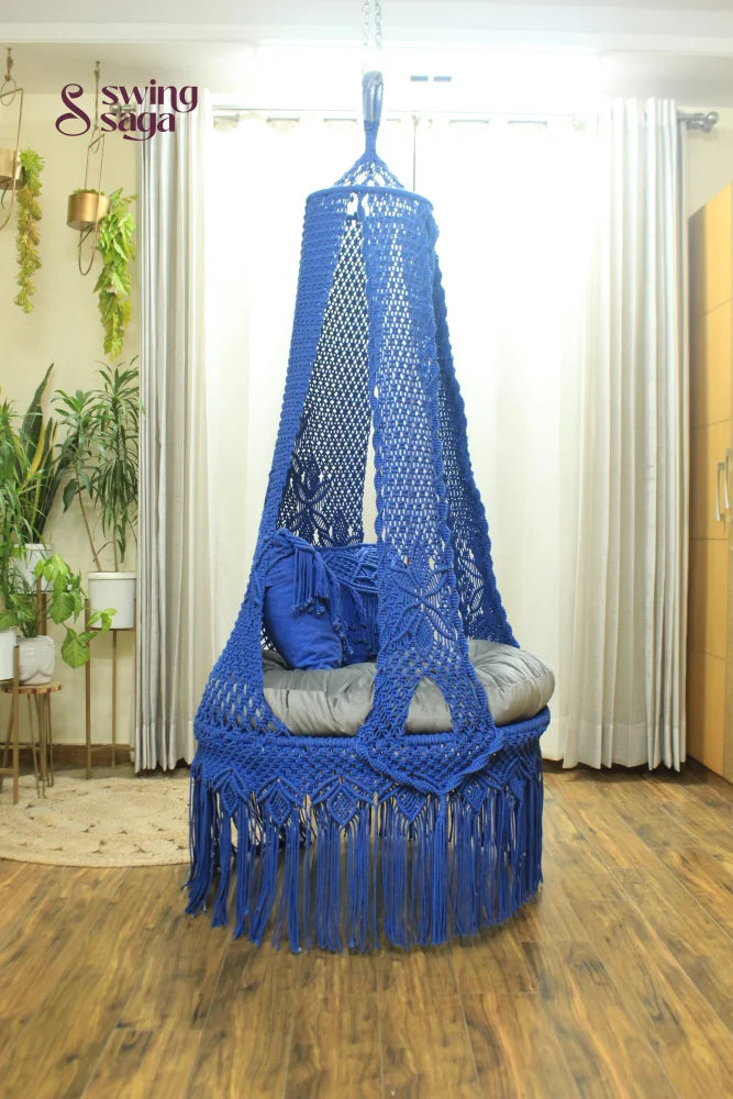 blue chair swing hanging in a room against white curtains.