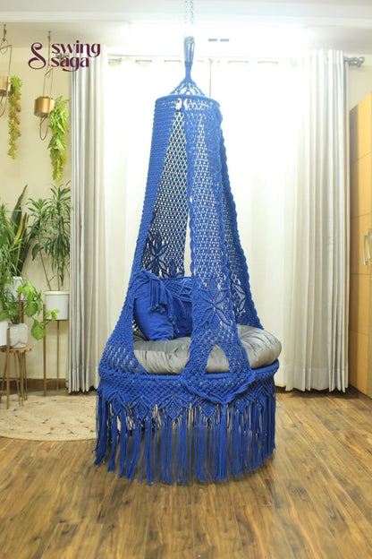 blue chair swing hanging in a room against white curtains.