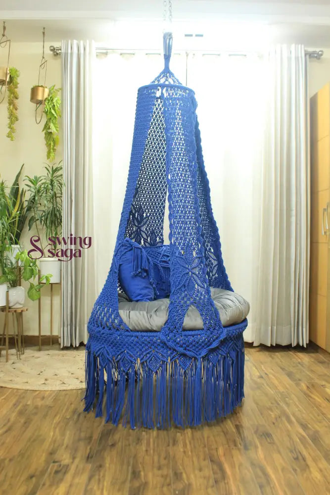 blue chair swing hanging in a room against white curtains.