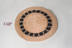 Round woven placemat with black circular patterns on a light gray background