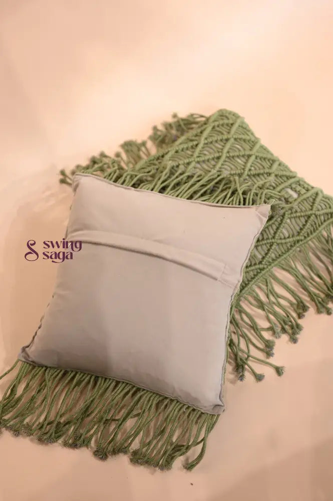 Grey pillow with green fringe on a beige background