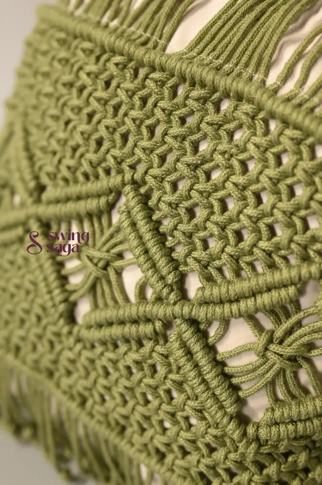 Close-up of a green macrame wall hanging with intricate patterns.