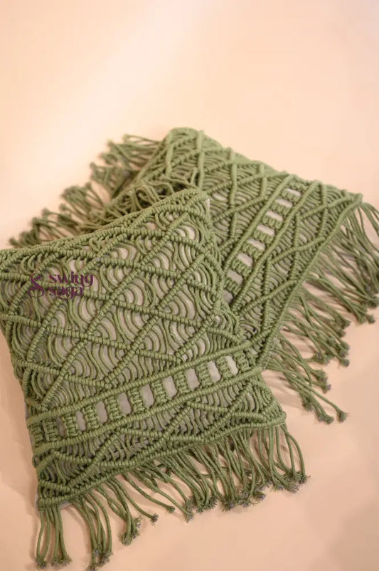 Green macrame throw blanket with fringes on a beige background