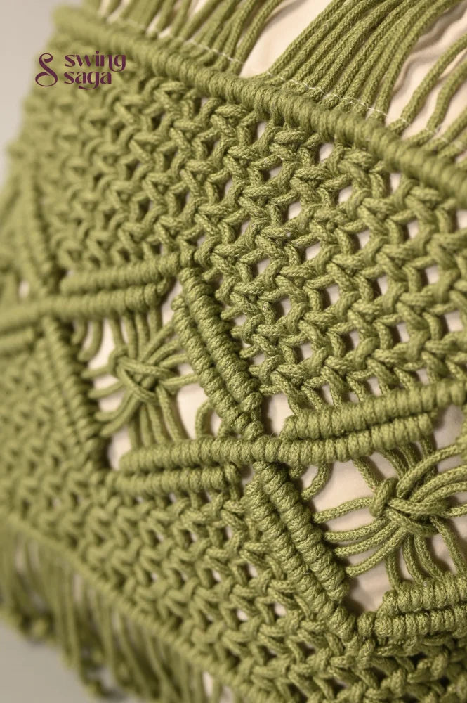Close-up of a green macrame wall hanging with intricate patterns.