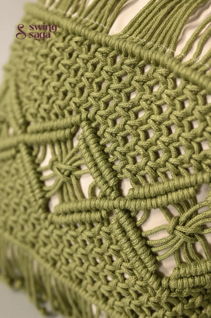 Close-up of a green macrame wall hanging with intricate patterns.