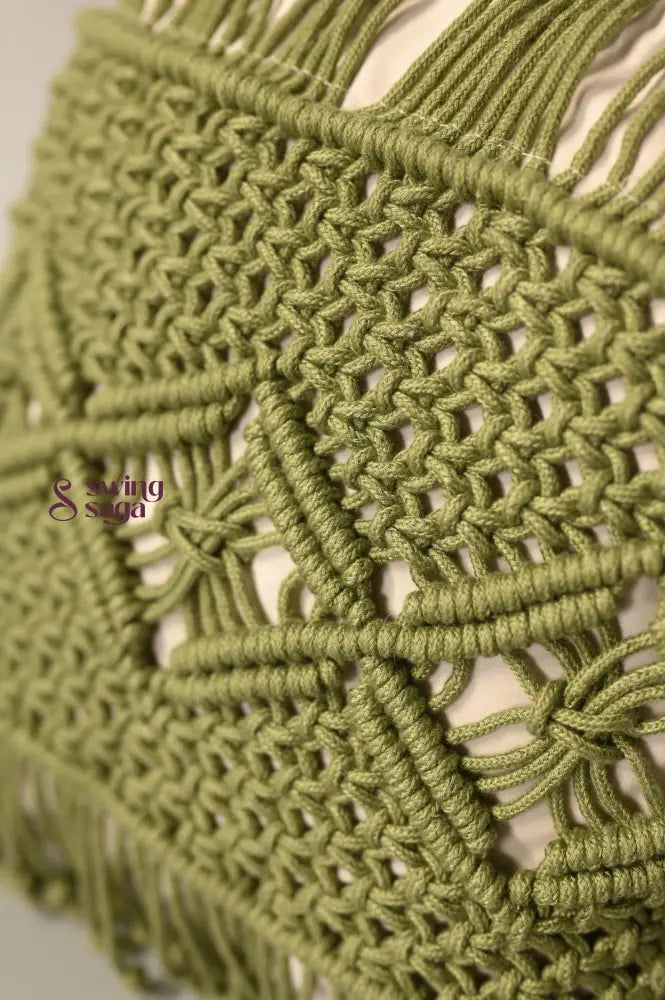 Close-up of a green macrame wall hanging with intricate patterns.