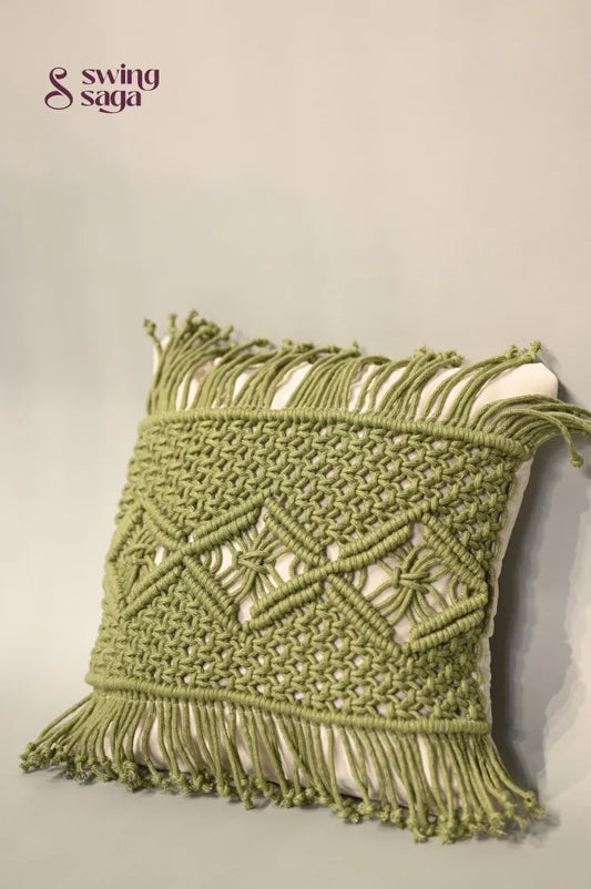 Green macrame wall hanging with intricate patterns on a neutral background