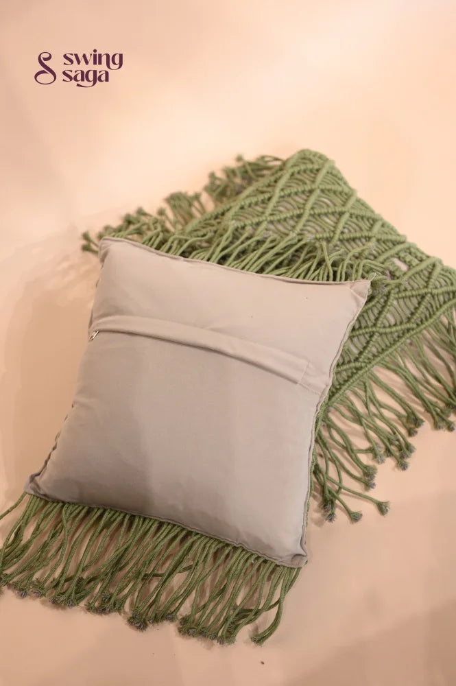 Grey pillow with green fringe on a beige background