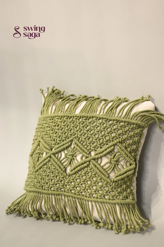 Green macrame wall hanging with intricate patterns on a neutral background