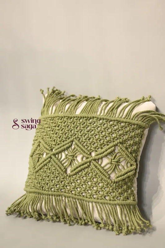 Green macrame wall hanging with intricate patterns on a neutral background