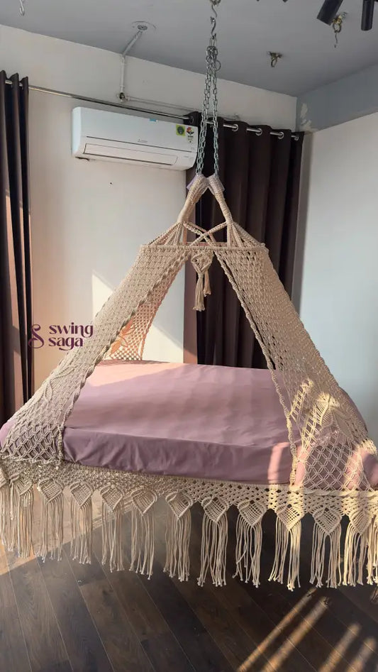 Macrame swing with a pink cushion in a room with an air conditioner and curtains.