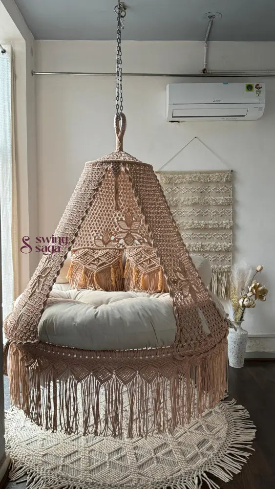Macrame hanging chair with tassels in a room with a wall-mounted air conditioner.