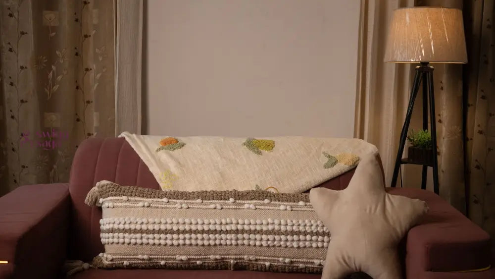 Sofa with a patterned blanket and pillow in a dimly lit room