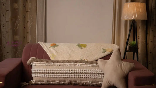 Sofa with a patterned blanket and pillow in a dimly lit room