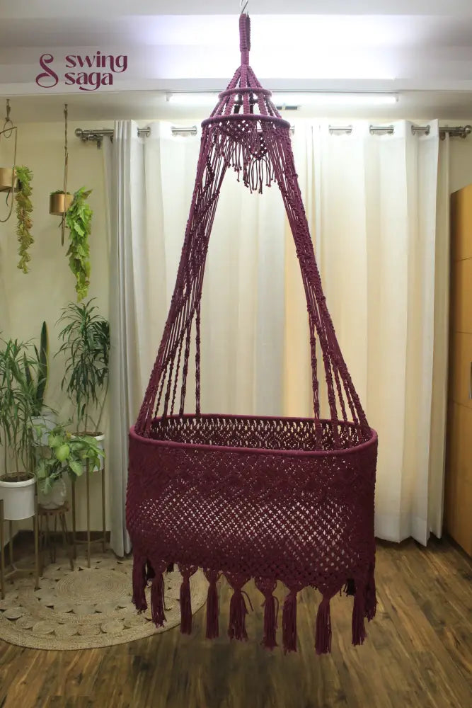 Brick Colored macrame baby bassinet hanging in an indoor setting.